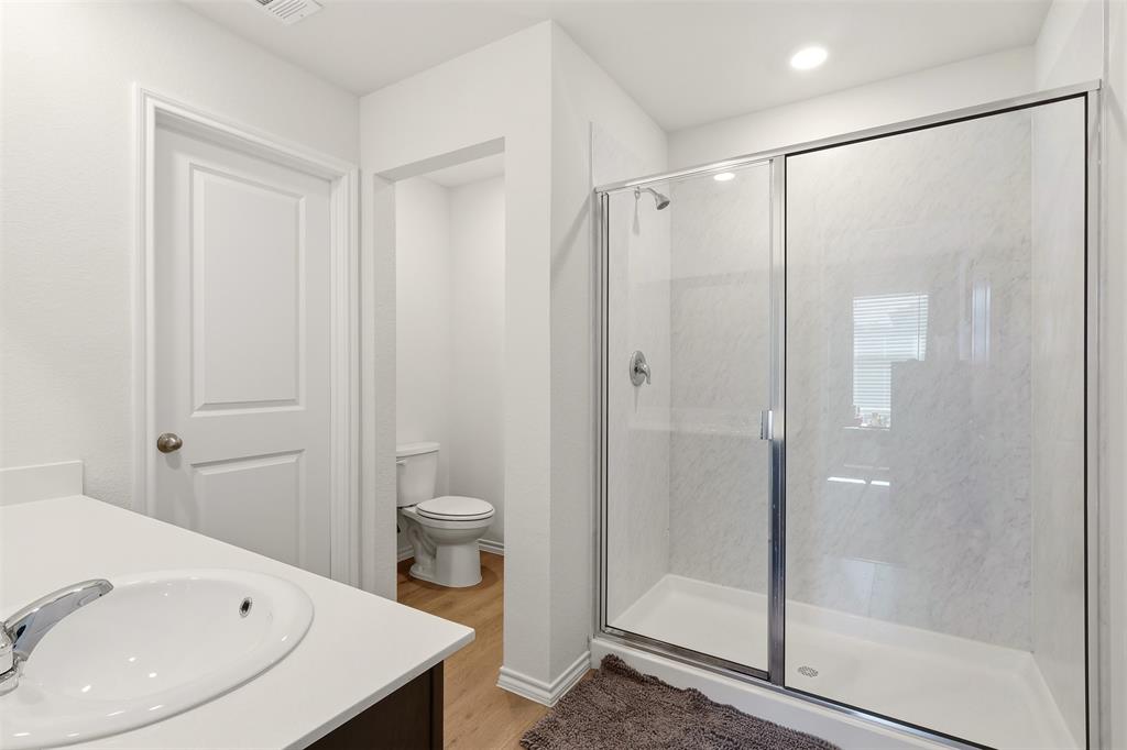 Full bathroom featuring a walk-in shower with a glass enclosure, a toilet, and a vanity with an integrated sink