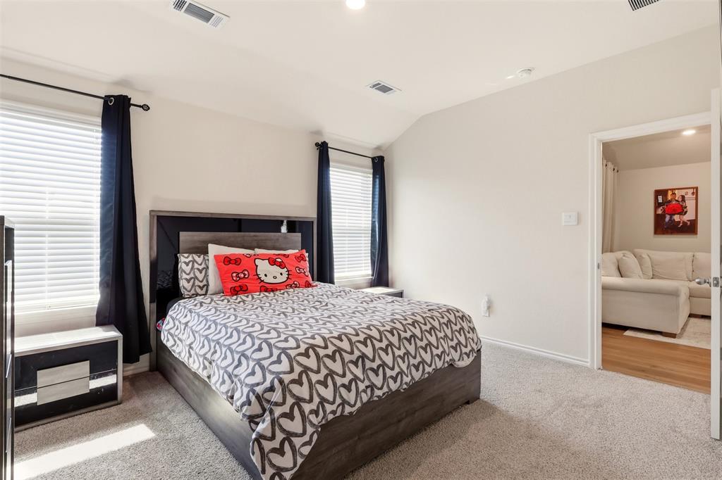 Bedroom featuring carpet flooring, two windows with blinds, and a built-in wall niche