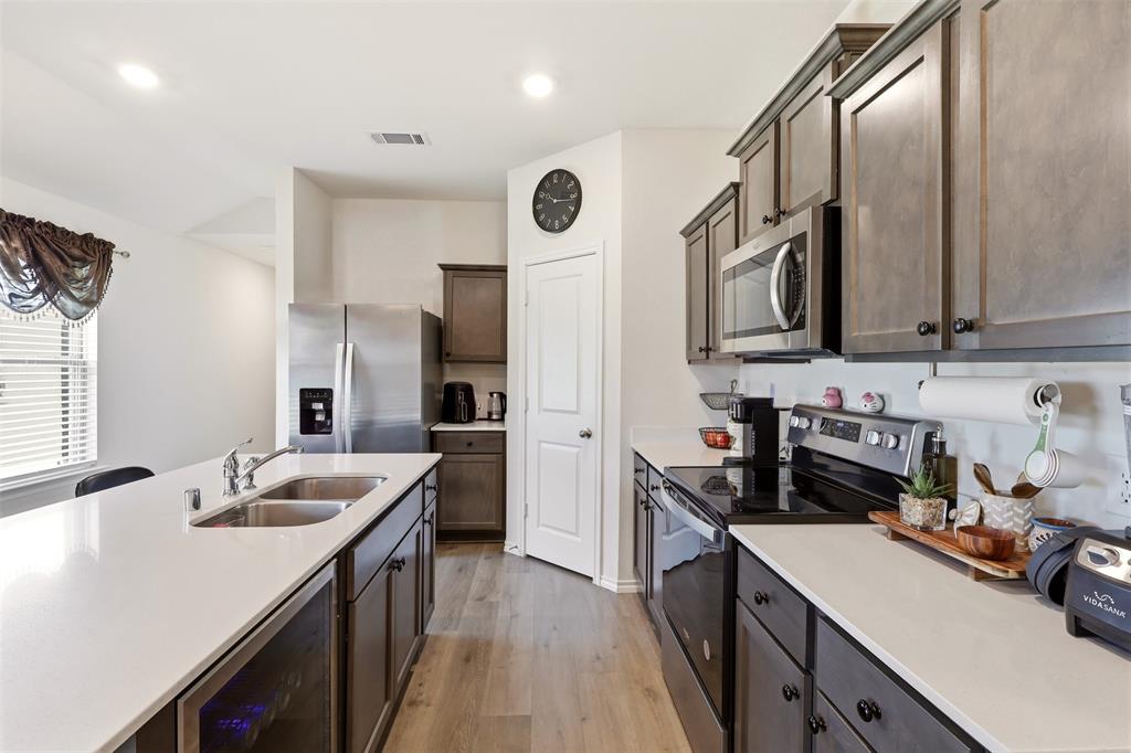 Kitchen featuring wood-finish flooring, stainless steel appliances, recessed lighting, white countertops, and shaker-style cabinetry