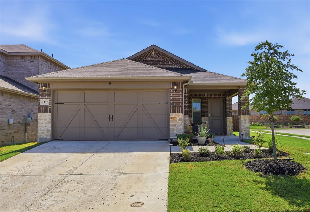 Brick and stone exterior with a covered porch, attached two-car garage, concrete driveway, and landscaped front yard Brick and stone exterior with a covered porch, attached two-car garage, concrete driveway, and landscaped front yard