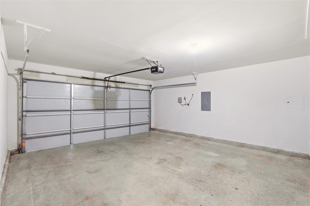 Attached garage with concrete flooring, automatic garage door opener, and white painted walls