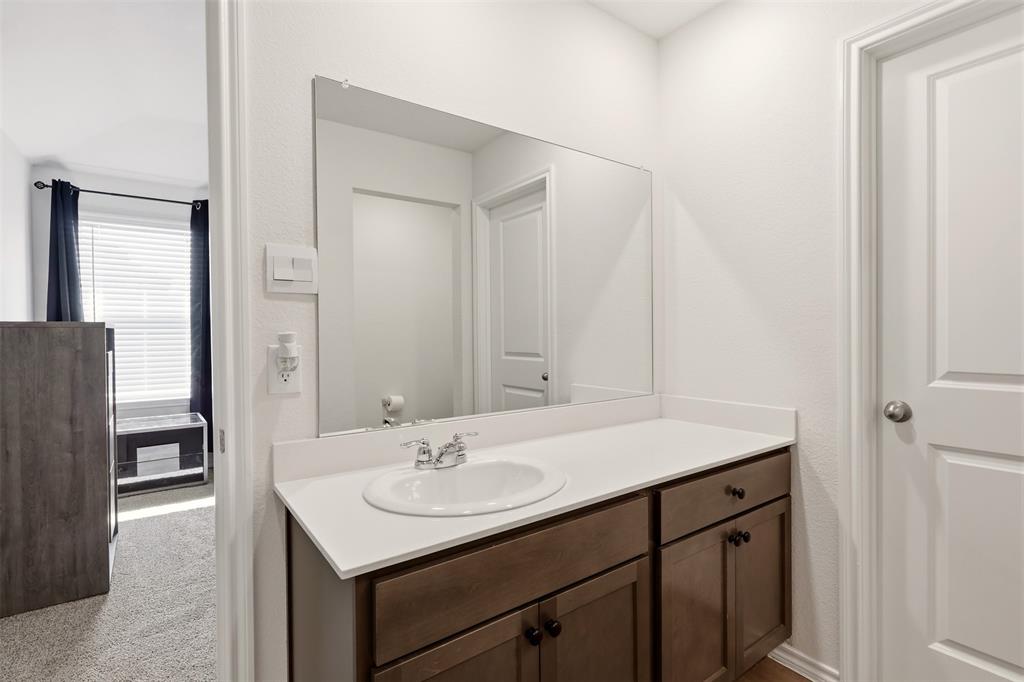 Vanity with a white countertop and integrated sink, dual-door cabinetry, a full-width mirror, and a privacy door