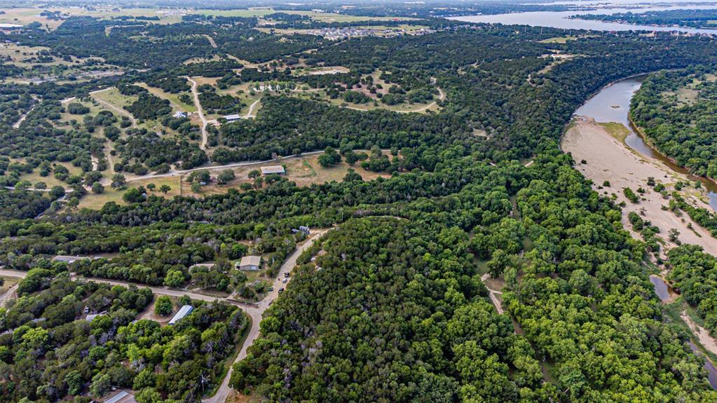 Expansive natural landscape featuring a winding river, dense tree coverage, and a distant body of water