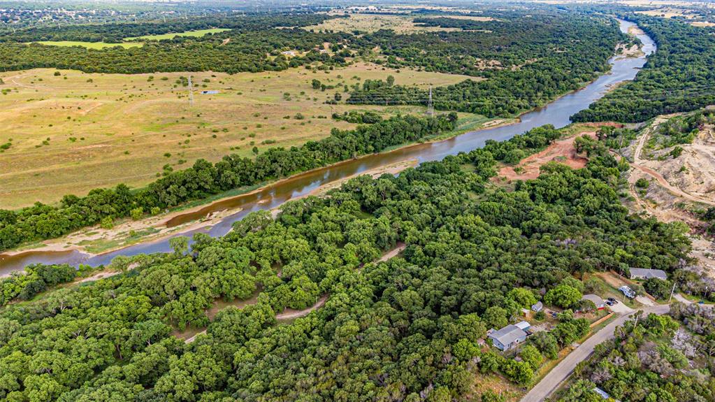Expansive natural landscape featuring a winding river, dense tree lines, open fields, and residential properties