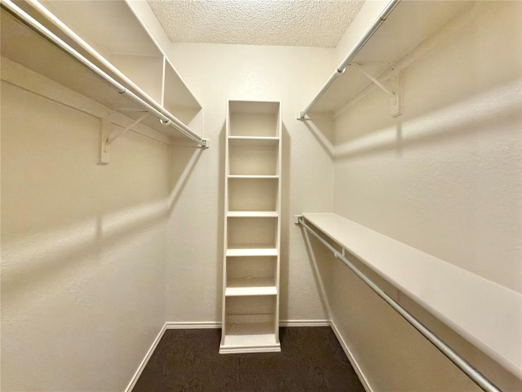 Built-in shelving, hanging rods, and dark wood-finish flooring