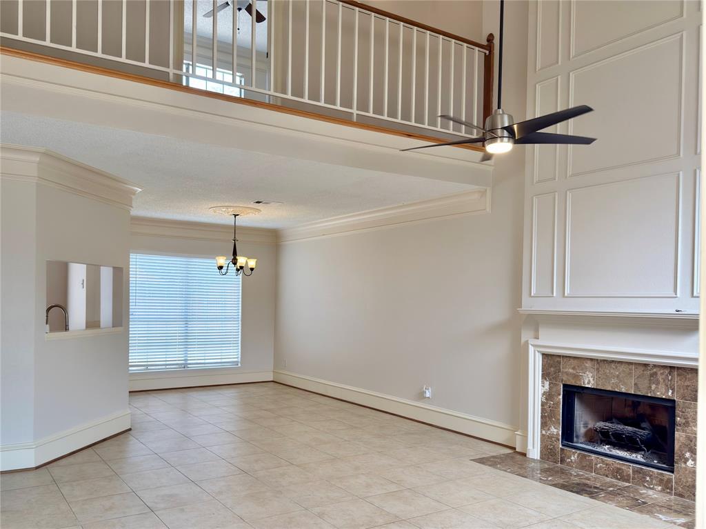 Two-story living area featuring a fireplace with a stone surround, decorative wall paneling, and a loft overlook