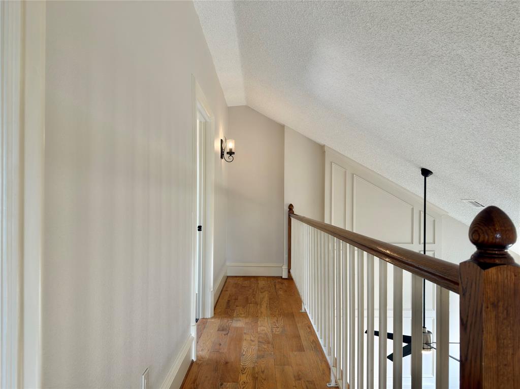Hardwood-style flooring throughout, white painted walls, and an angled ceiling