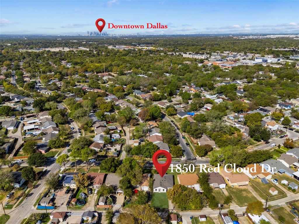 Aerial perspective of property featuring mature trees and a manicured lawn, positioned within a residential neighborhood with a distant cityscape