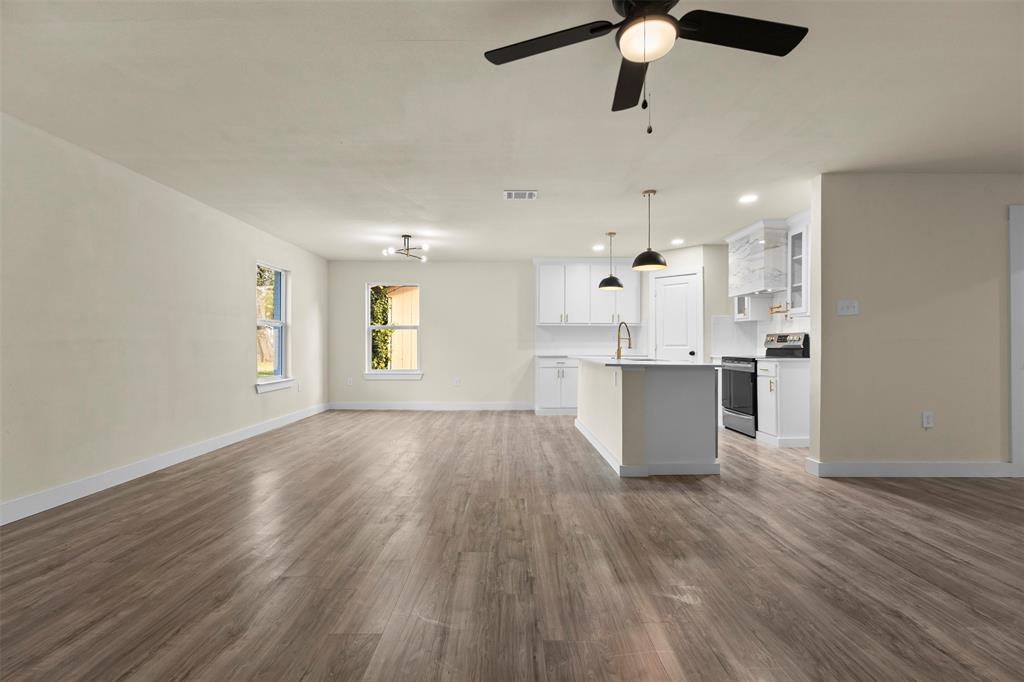 Open-concept area featuring wood-finish flooring, white cabinetry, a center island with pendant lighting, and recessed ceiling lights