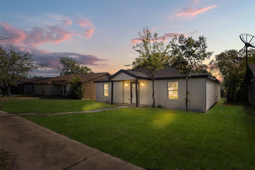 Single-story residence featuring a painted brick exterior, gabled entryway, concrete walkway, and landscaped front lawn