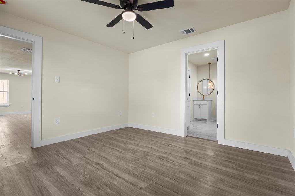 Neutral-toned interior featuring wood-finish flooring, a ceiling fan with integrated lighting, and white door casings