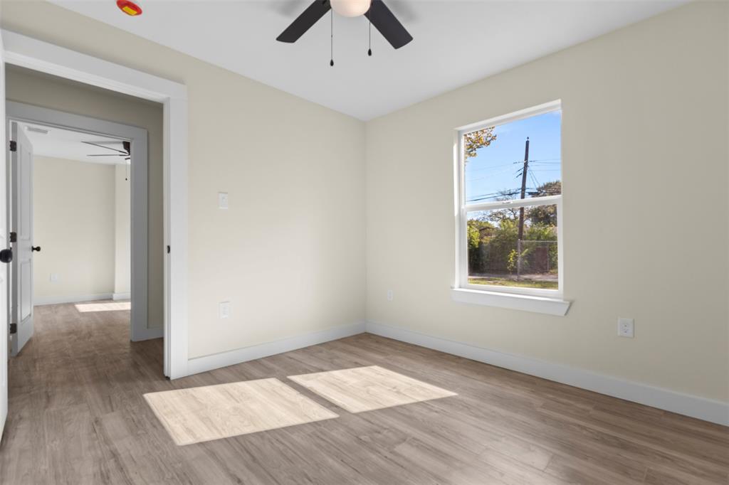 Room featuring wood-finish flooring, a single-hung window, and a ceiling-mounted light fixture with fan
