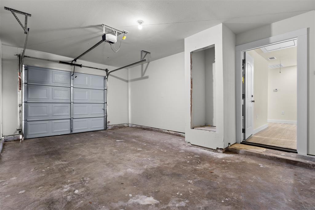 Enclosed garage featuring an automated overhead door, concrete flooring, and a built-in recessed wall niche