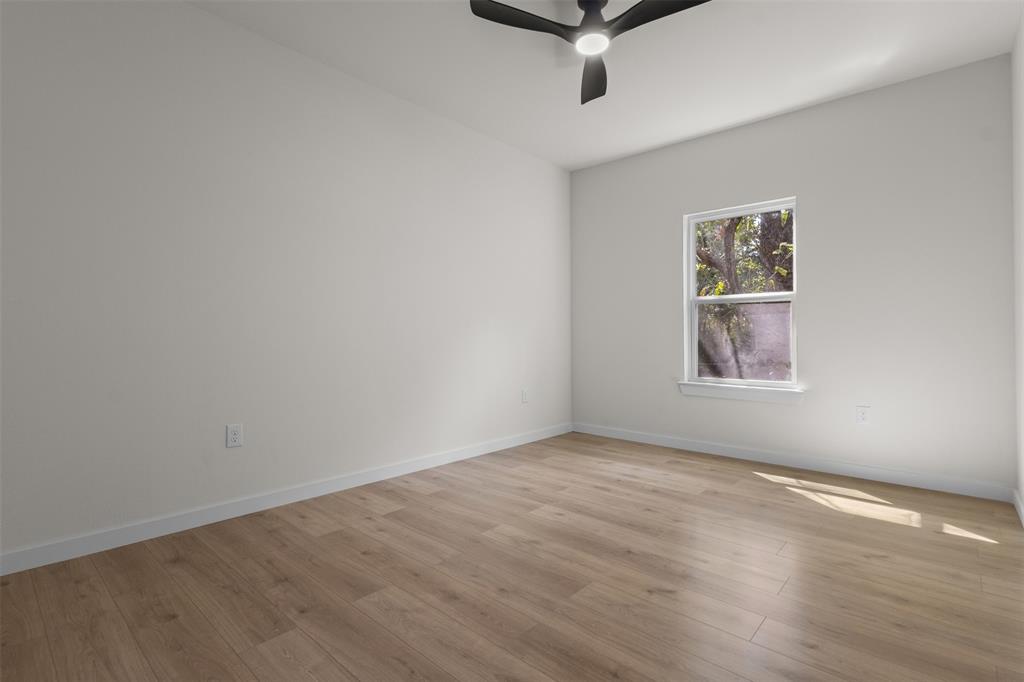Neutral wall color, wood-finish flooring, single window, white trim, and a ceiling fan