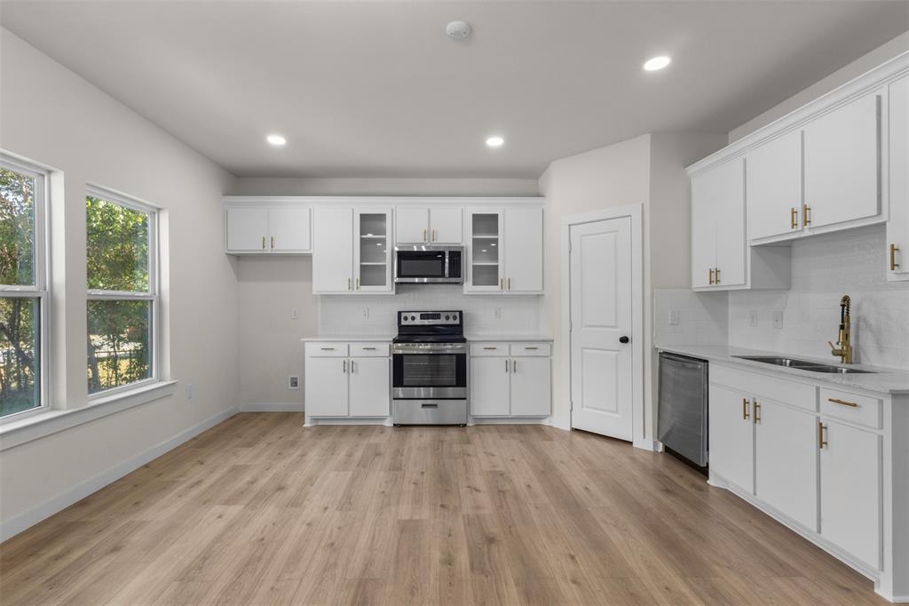 Spacious kitchen with wood-finish flooring, white cabinetry, stainless steel appliances, and recessed lighting Spacious kitchen with wood-finish flooring, white cabinetry, stainless steel appliances, and recessed lighting
