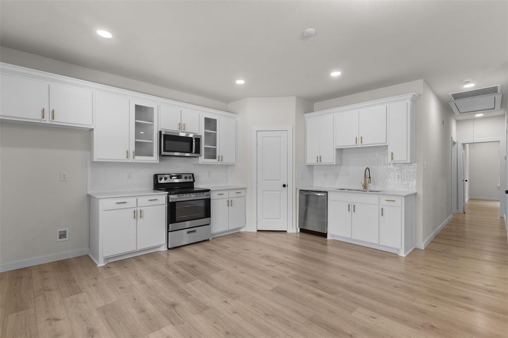 Kitchen featuring white cabinetry, stainless steel appliances, wood-finish flooring, recessed lighting, and a subway tile backsplash