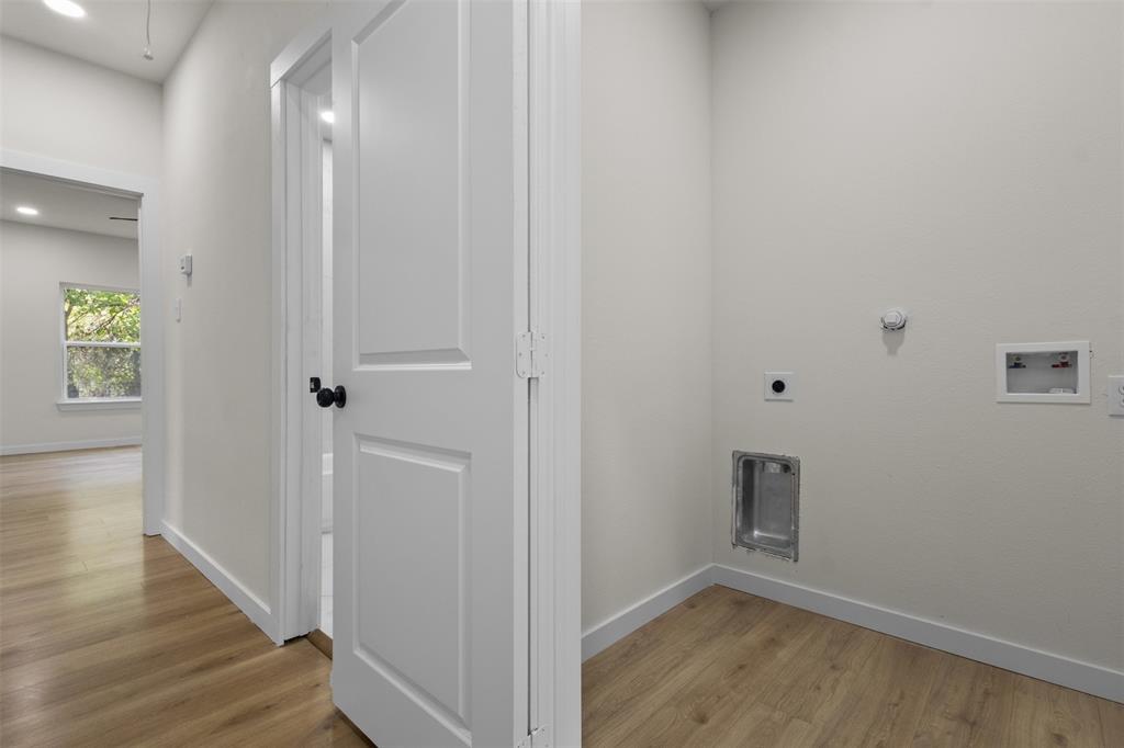 Dedicated laundry area with hookups, wood-finish flooring, and crisp white walls