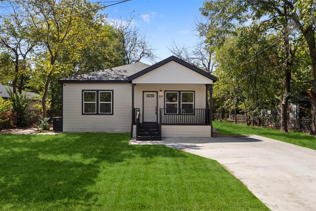 Light-toned siding exterior with dark trim accents, covered front porch, dark-railed steps, asphalt shingle roof, and a concrete driveway Light-toned siding exterior with dark trim accents, covered front porch, dark-railed steps, asphalt shingle roof, and a concrete driveway
