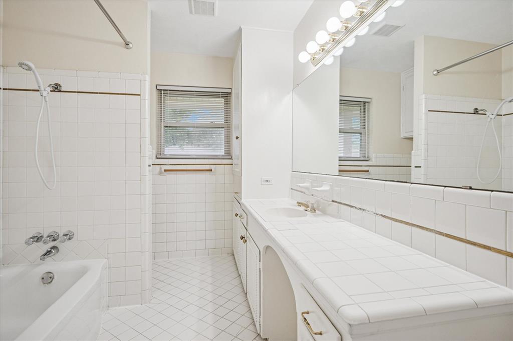 Hall bath with tub and showerhead. Opens to bedroom three.