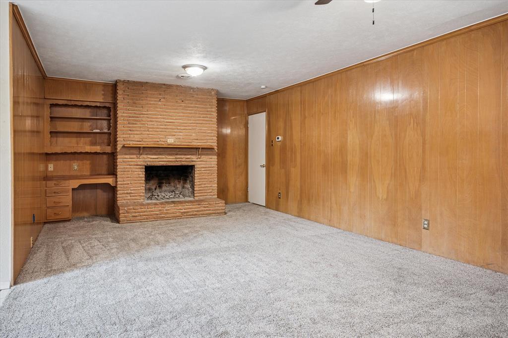 Be cozy all winter with two fireplaces! Here's the second WBFP with gas starter. Natural wood-paneled den with built-in desk and shelves opens to covered patio.