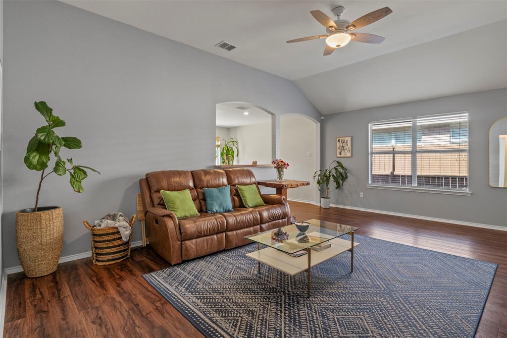 Vaulted ceiling with a ceiling fan, wood-finish flooring, and multiple windows
