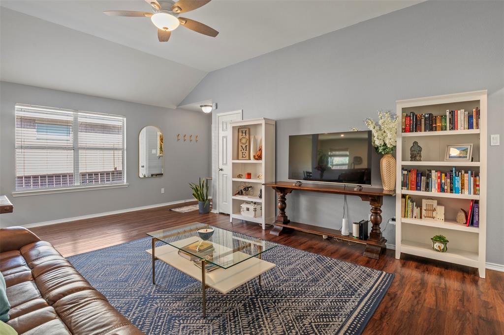 Vaulted ceiling with ceiling fan, wood-finish flooring, multiple windows, and built-in shelving