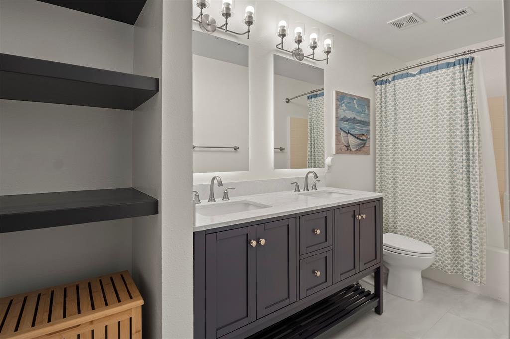 Dual vanity with white countertop, chrome fixtures, and dark cabinetry