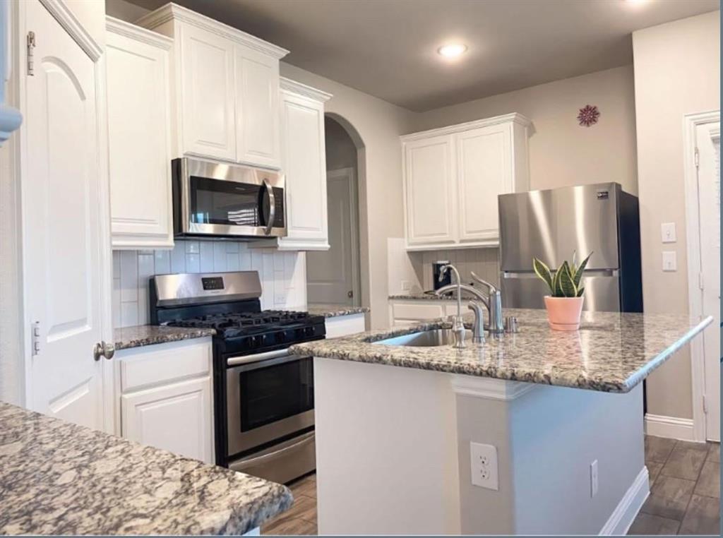Kitchen featuring white cabinetry, stainless steel appliances, granite countertops, and subway tile backsplash