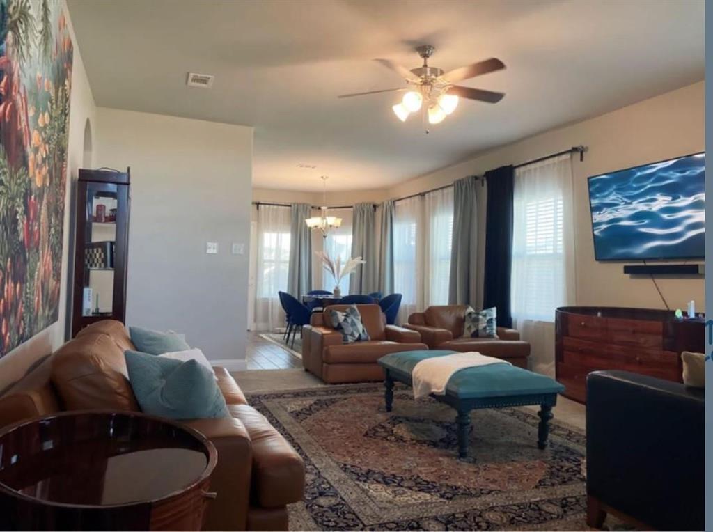 Living area featuring a ceiling fan with integrated lighting, multiple windows with blinds, and an arched entryway