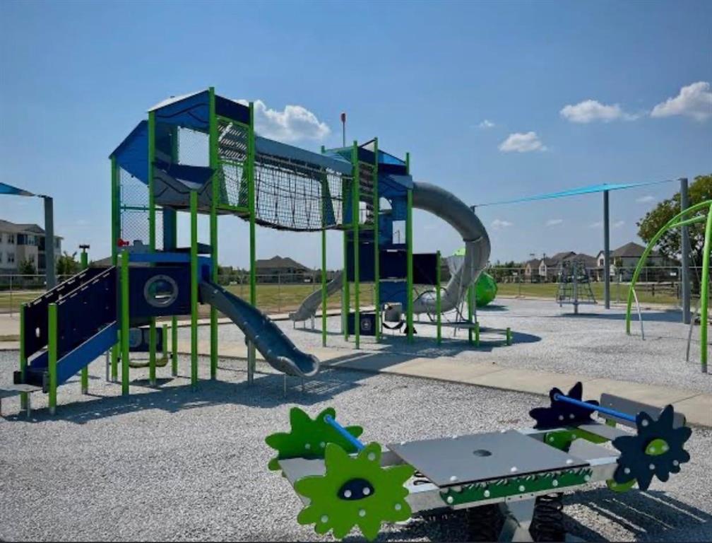 Outdoor play area featuring a multi-level play structure, tube slide, open slide, and a spring rider