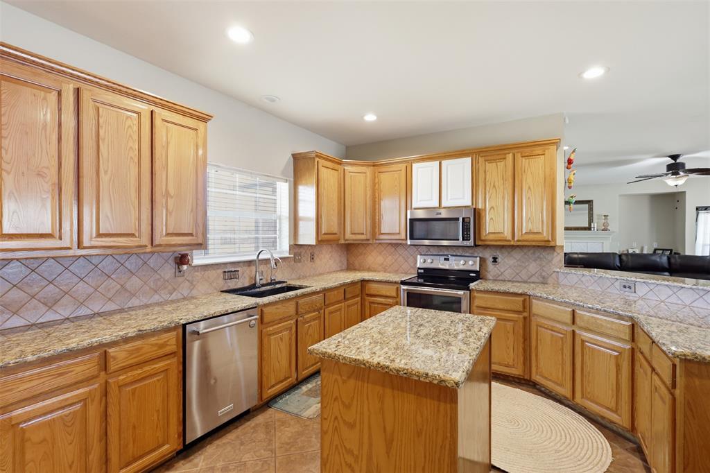 Large kitchen features island, granite countertops, stainless steel appliances and natural wood cabinets.