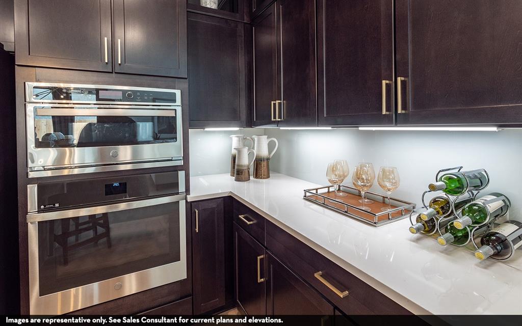 Dark wood-finish cabinetry with gold-tone hardware, white countertops, built-in stainless steel microwave, and built-in stainless steel oven Dark wood-finish cabinetry with gold-tone hardware, white countertops, built-in stainless steel microwave, and built-in stainless steel oven