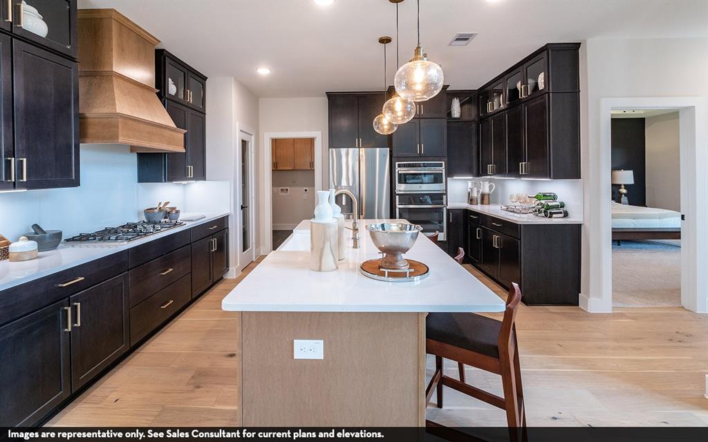 Spacious kitchen featuring dark wood cabinetry, a light wood-finish island, and light wood-finish flooring Spacious kitchen featuring dark wood cabinetry, a light wood-finish island, and light wood-finish flooring