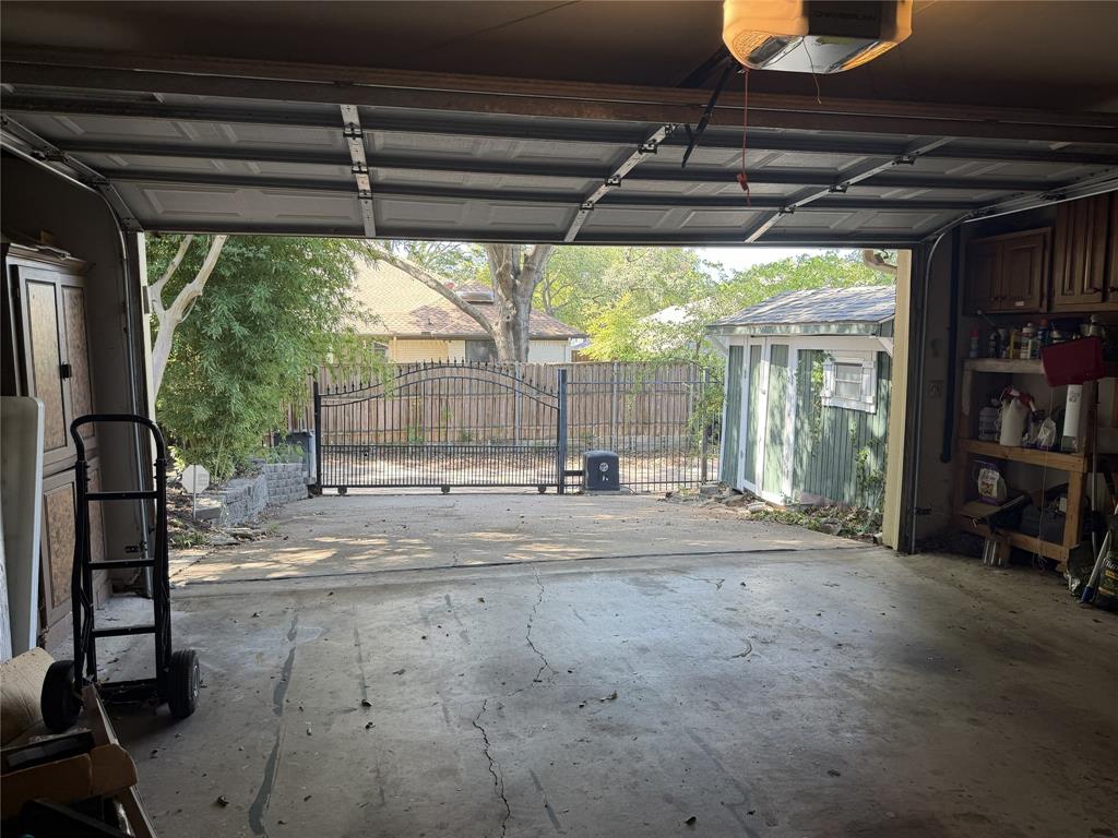 Garage with automatic opener, featuring built-in storage cabinetry, and an exterior wrought iron gate.