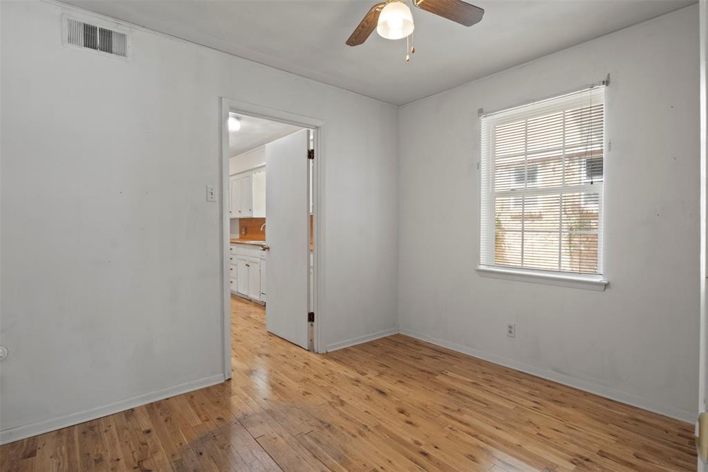 Wood-finish flooring throughout, white walls, and a window with blinds