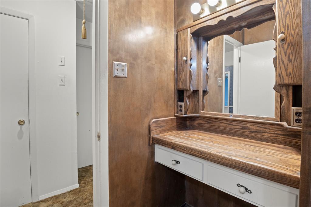 Built-in vanity with wood-finish countertop, integrated mirror, and dual vanity lights