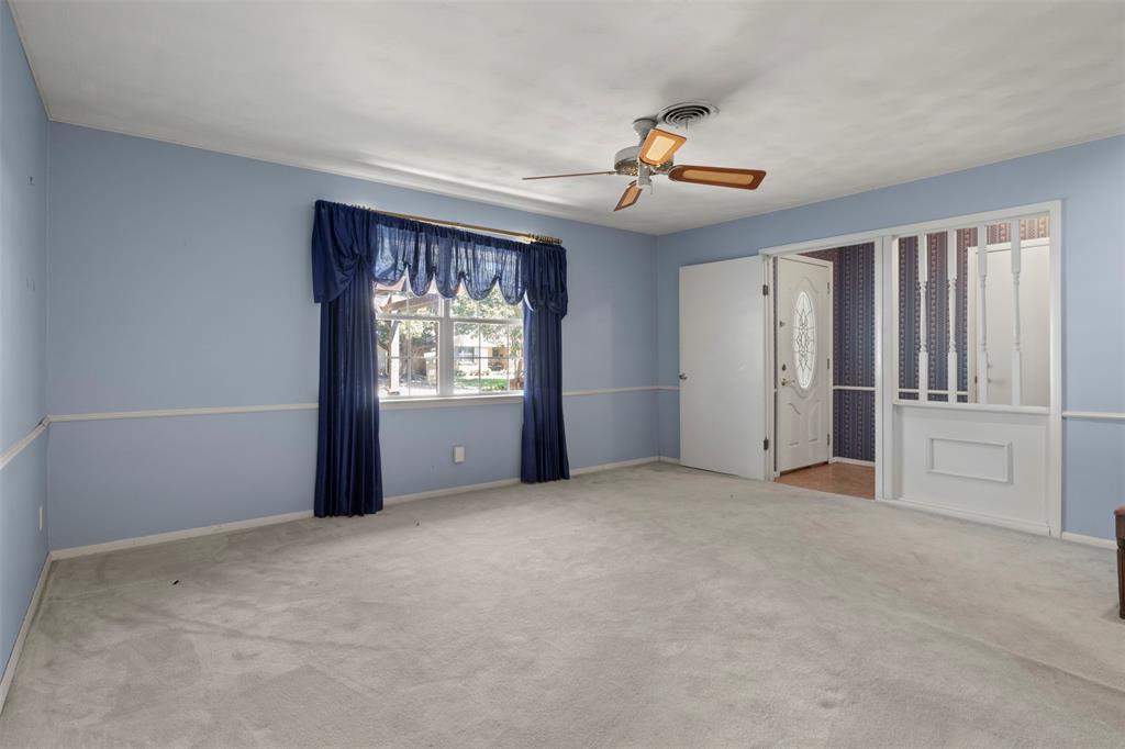 Carpeted room featuring a ceiling fan, a window with exterior views, and a paneled entry door with decorative glass Carpeted room featuring a ceiling fan, a window with exterior views, and a paneled entry door with decorative glass