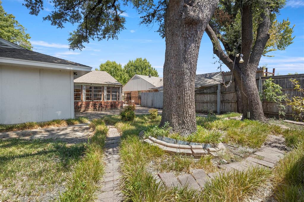 Backyard with mature trees, screened porch, and brick paver pathway