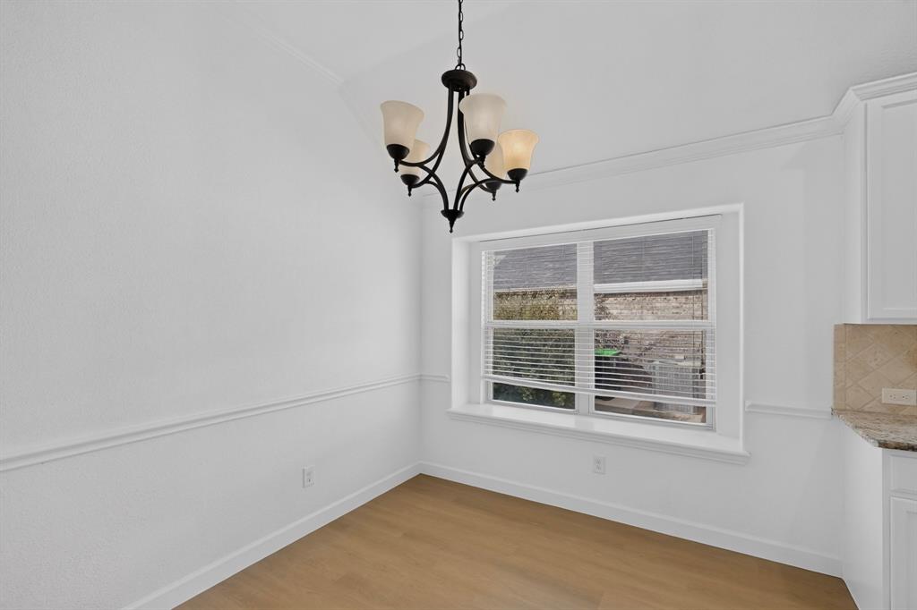 Space featuring wood-finish flooring, chair rail molding, a multi-arm chandelier, and a recessed window with deep sill