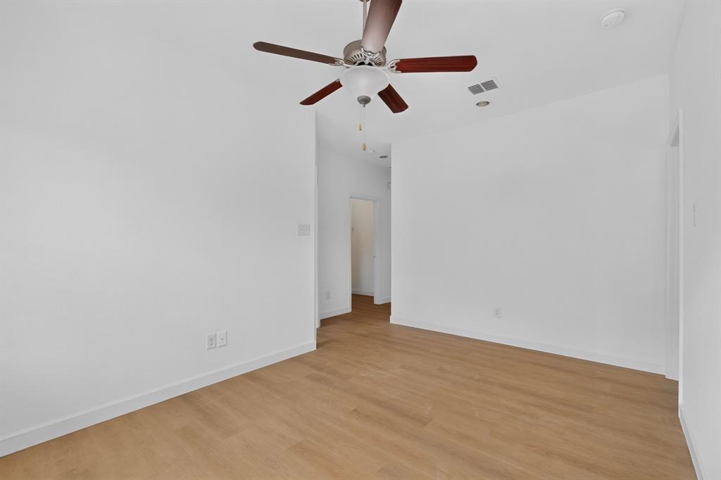 Neutral interior featuring wood-finish flooring, white walls, and a ceiling fan with integrated lighting