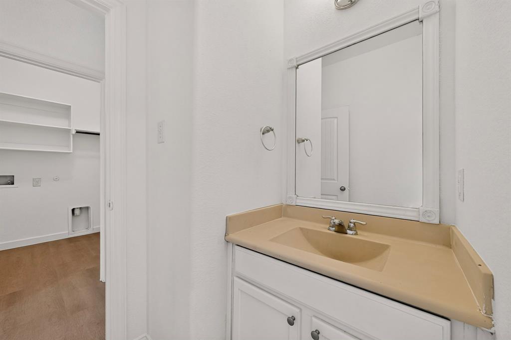 Vanity featuring a molded countertop with integrated sink, white cabinetry, wall-mounted mirror, and metal hardware