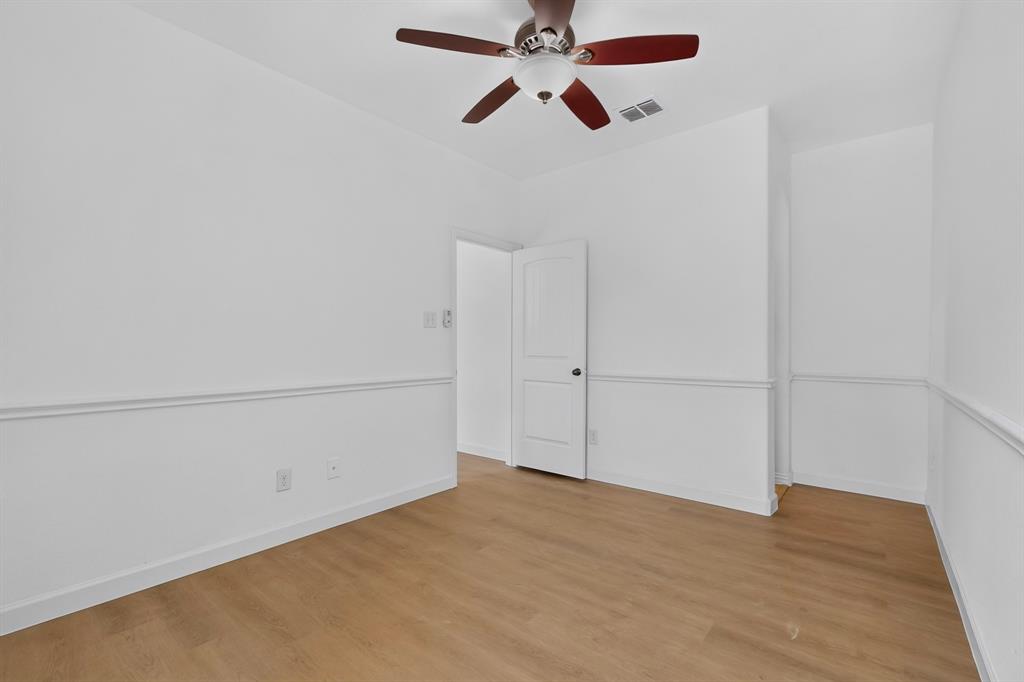 Room featuring wood-finish flooring, white walls with chair rail trim, and a ceiling fan with integrated lighting