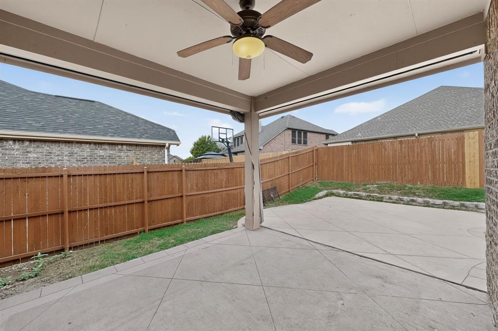 Covered patio featuring a scored concrete floor, ceiling fan with integrated lighting, and a brick exterior wall