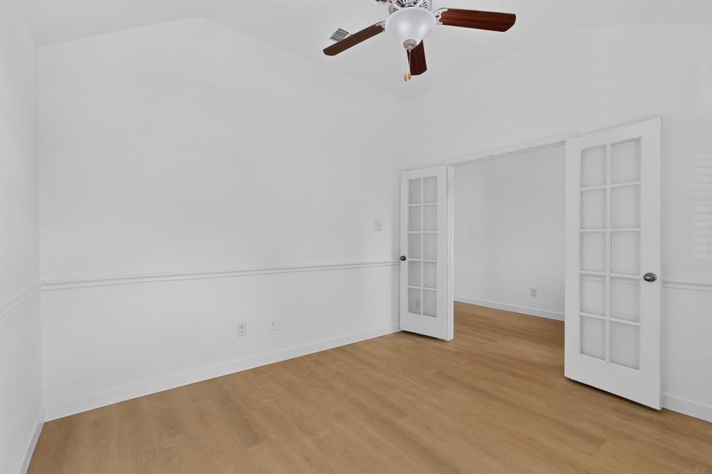 Vaulted ceiling room featuring wood-finish flooring, white chair rail molding, and a ceiling fan