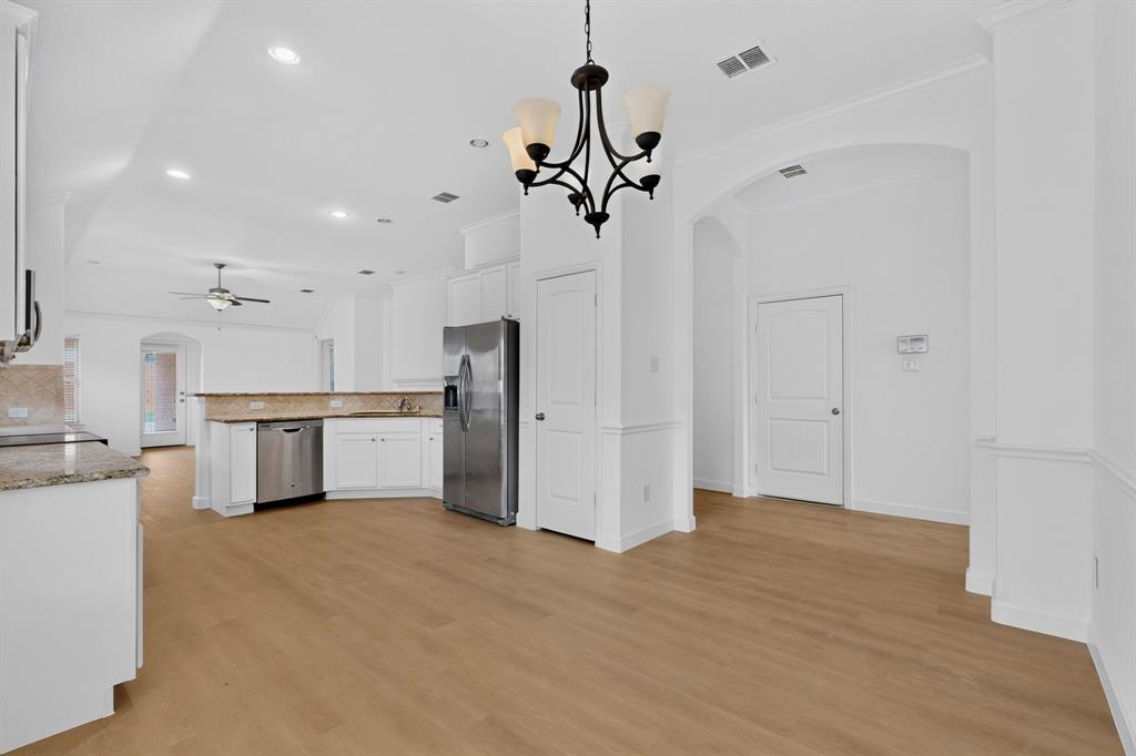 Kitchen featuring white cabinetry, stone-surface countertops, wood-finish flooring, an arched entryway, and a multi-arm chandelier