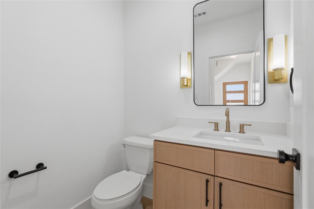 Wood-finish vanity with white countertop, undermount sink, and brass-finish faucet