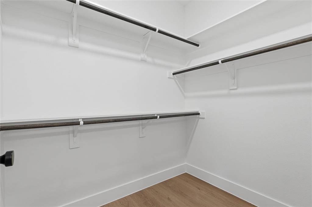 Walk-in closet featuring built-in shelving, hanging rods, and wood-finish flooring
