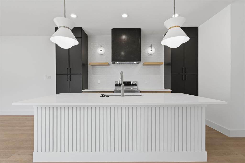 Kitchen island with vertical slat detailing and a solid surface countertop, equipped with a stainless steel faucet