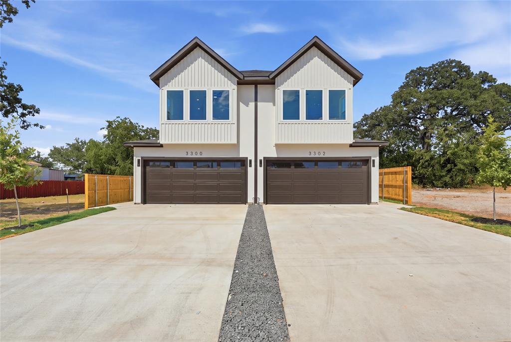Modern duplex exterior with white vertical siding, prominent dark brown garage doors, and individual concrete driveways