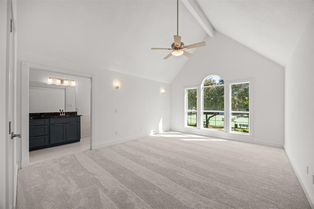 Large Master Bedroom showing cathedral ceiling, ceiling fan, new wall sconces, new double insulated, low E, glass windows and entrance to the Master Bath.